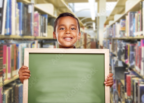 Smiling Hispanic Boy Holding Empty Chalk Board in Library