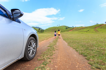 Front of car and mother with child at the grass hill in Ranong p