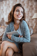 © Drobot Dean - Happy young woman is sitting on sofa and holding tablet