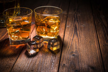 Two Glasses Of Whiskey With Ice On Wooden Table