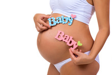 Close-up Of Pregnant Tummy With Blue And Pink Labels "Baby" For Newborn Girl, Boy Or Twins.