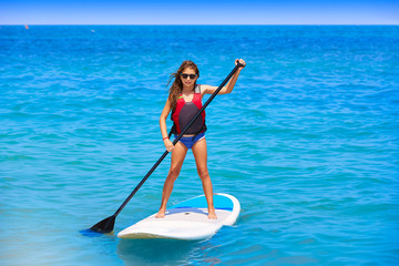 Kid paddle surf surfer girl with row in the beach