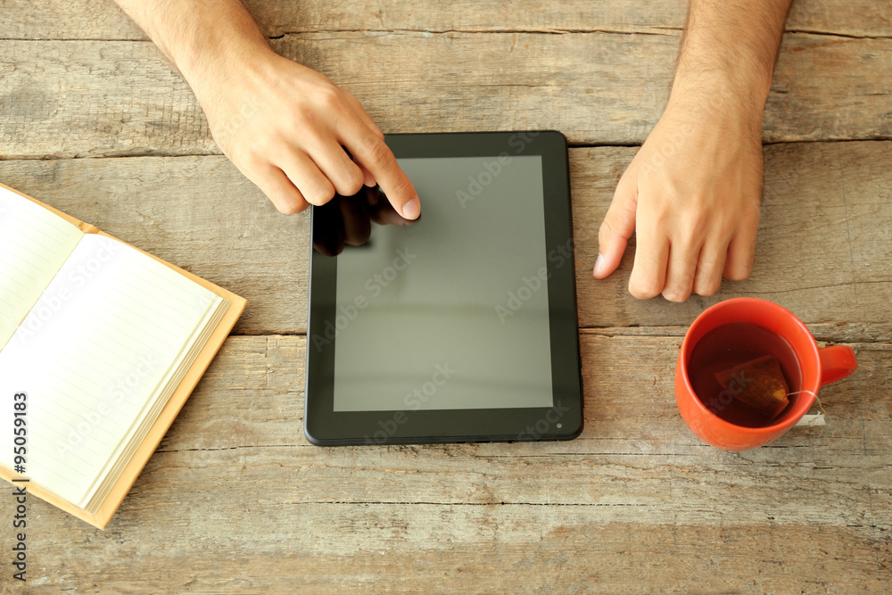 Workplace - tablet, book and red cup of tea on wooden table