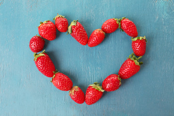 Wall Mural - Heart shaped strawberries on blue wooden background