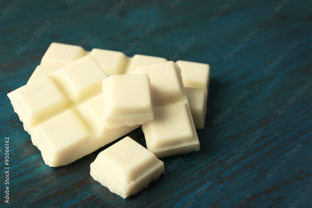 White chocolate pieces on color wooden background