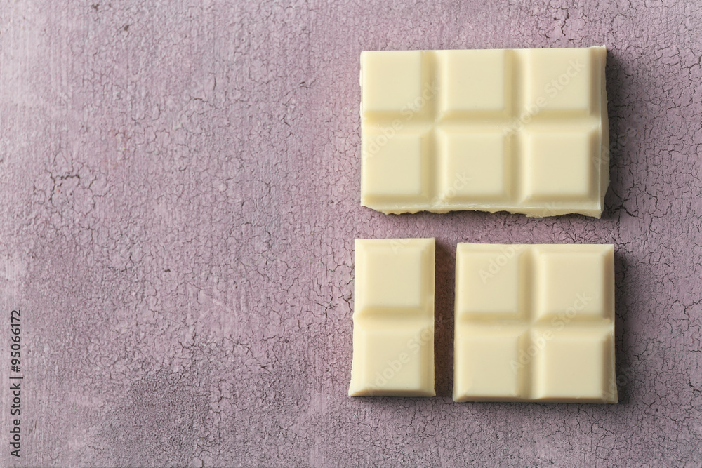 White chocolate pieces on color wooden background