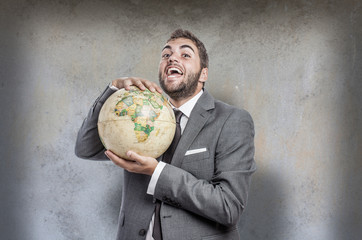 evil young business man holding a world globe agianst a grunge w