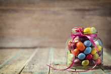 Colorful Candy Jar Decorated With A Bow Against Rustic Wooden Background, Birthday Concept