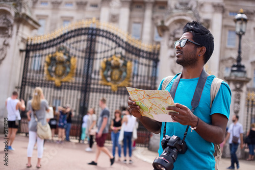 Cuadros en Lienzo Indian tourist outside buckingham palace holding a map and his camera