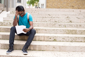 young man reading a letter in the street