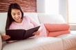 © WavebreakmediaMicro - Smiling asian woman on couch reading