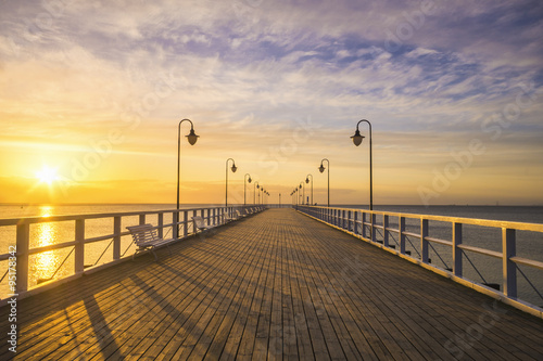 Fototapeta na wymiar wooden pier by the sea lit by stylish lamps at night 