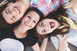 © kegfire - Closeup of three best friends lying down and laughing. Teenage people wearing casual clothes smiling. Top view