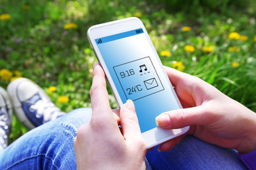 Poster - Young woman with mobile phone sitting on green grass outdoors