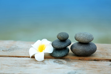 Poster - Pebbles with plumeria flower on wooden background