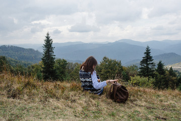 Canvas Print - beautiful happy stylish traveling girl sitting in the mountains