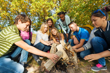 International friends construct bonfire together