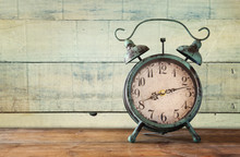 Image Of Vintage Alarm Clock On Wooden Table In Front Of Wooden Background. Retro Filtered
