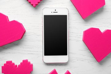 Wall Mural - Smart phone with blank screen and hearts on wooden table