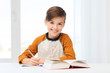 © Syda Productions - smiling student boy writing to notebook at home