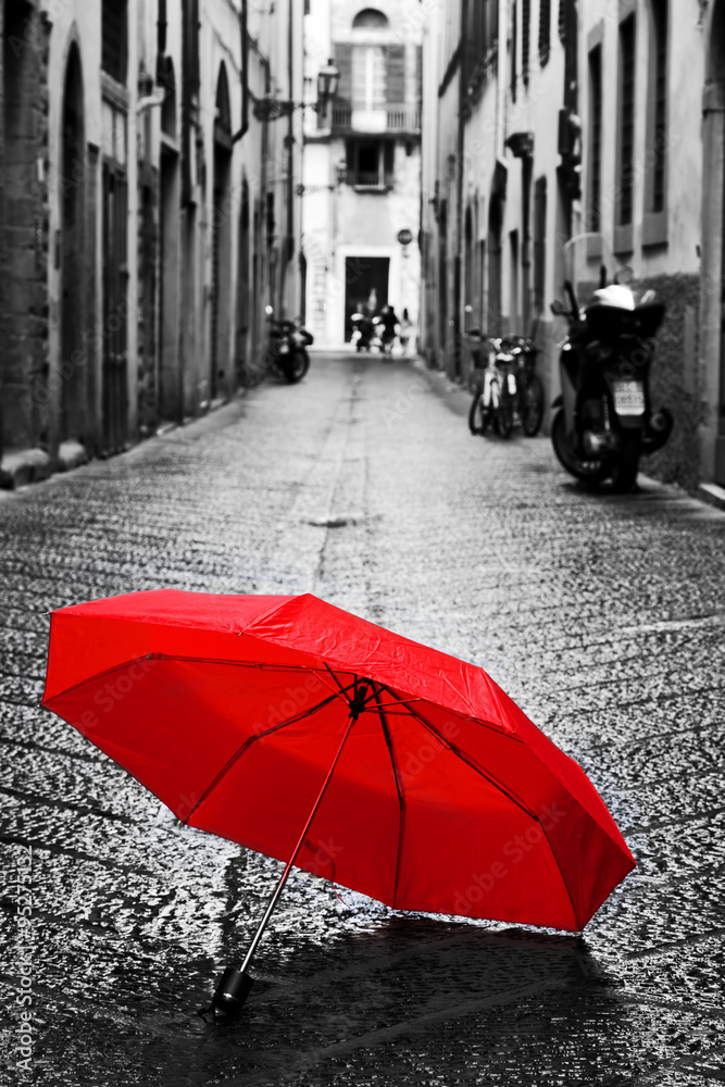 Red umbrella on cobblestone street in the old town. Wind and rain - obrazy, fototapety, plakaty 