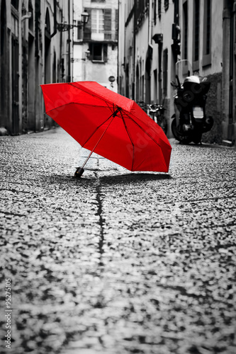 Naklejka na meble Red umbrella on cobblestone street in the old town. Wind and rain