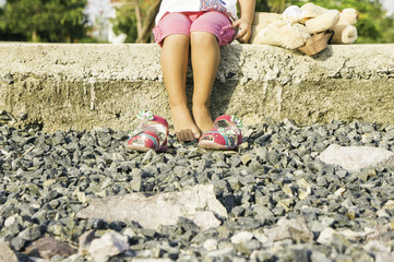 beautiful little girl sitting on the waterfront and plays.