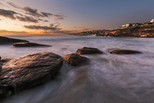 Sunrise Seascape With Rocks And Flowing Water On Long Exposure A