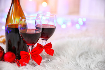 Wall Mural - Bottle and glasses of wine with Christmas decor against colorful bokeh lights background