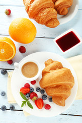 Wall Mural - Fresh tasty croissants with berries on blue wooden background