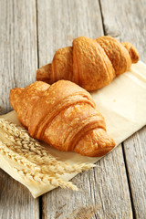 Wall Mural - Tasty croissants with spikelets on grey wooden background