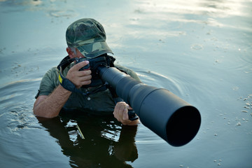 Wall Mural - wildlife photographer outdoor, standing in the water
