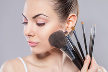 Beauty Girl With Makeup Brushes. Perfect Smooth Skin.Applying Makeup.Beautiful Young Woman Holding Different Make Up Brushes