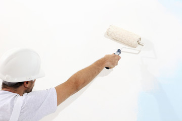 Wall Mural - painter man at work with a paint roller, wall painting concept