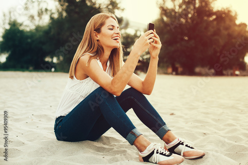 Fototapeta na szkło Młoda kobieta, wpisując wiadomość na telefon