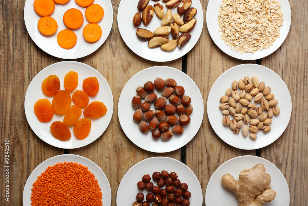 Different products on saucers on wooden table, top view