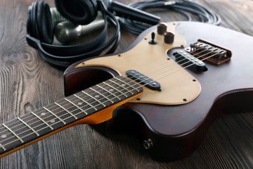 Wall Mural - Electric guitar with microphones and headphones on wooden table close up