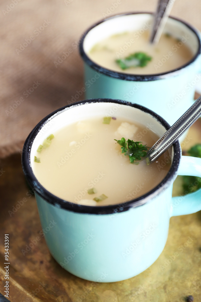 Mugs of soup on metal tray on a table
