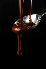 Canvas Print - Chocolate poured on a spoon on dark background