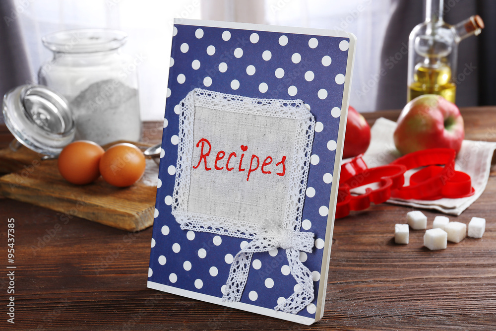 Recipe book and ingredients for cooking on a table in kitchen