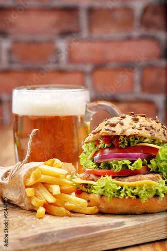 Grilled hamburger with fries and beer on brick wall background © wideonet