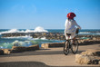 Woman in red hat by bicycle on seafront