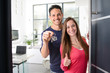 © W PRODUCTION - happy young couple at their new house front door proud to show home keys