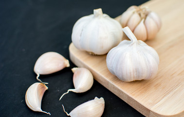 garlic clove, garlic bulb place on chopping block on black backg