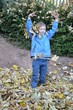 Kind hat Spaß mit Herbstlaub bei der Gartenarbeit 