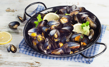 Copper Pot Of Mussels Garnished With Lemon Slices.