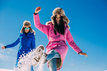 Two girlfriends have fun and enjoy the fresh snow on a beautiful