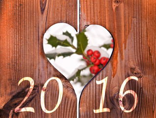 Wall Mural - 2016, wooden frame in the shape of a heart and branch of holly under the snow in the background