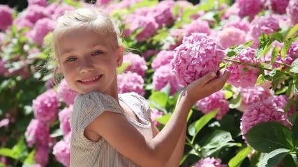 happy little girl smelling a flower and smiling at the camera