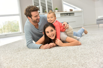 Parents and baby girl laying on carpet,